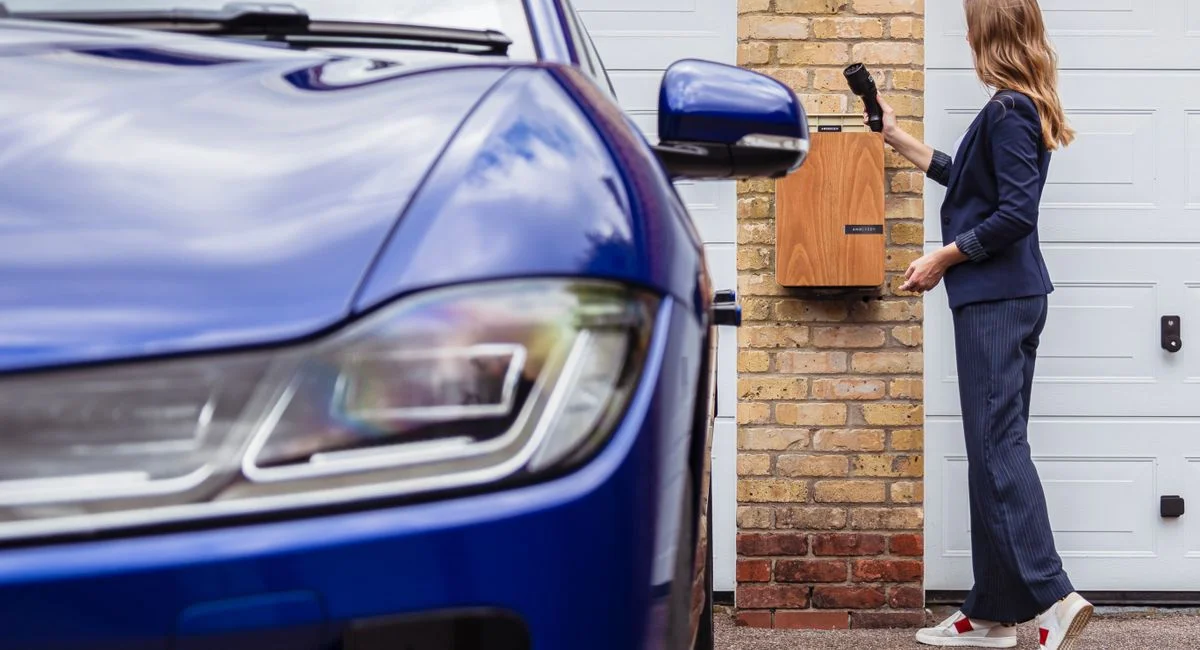 Woman charging an electric car at a home station, promoting sustainability.