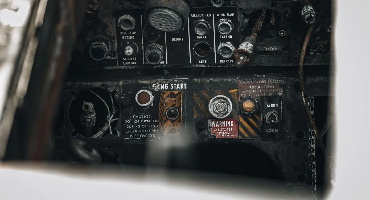 Close-up of a vintage aircraft control panel featuring worn buttons and labels.