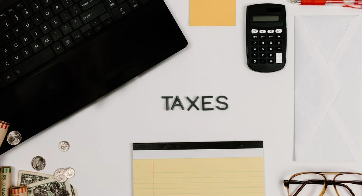 Organized office supplies for managing taxes, featuring a calculator, keyboard, and notepad.