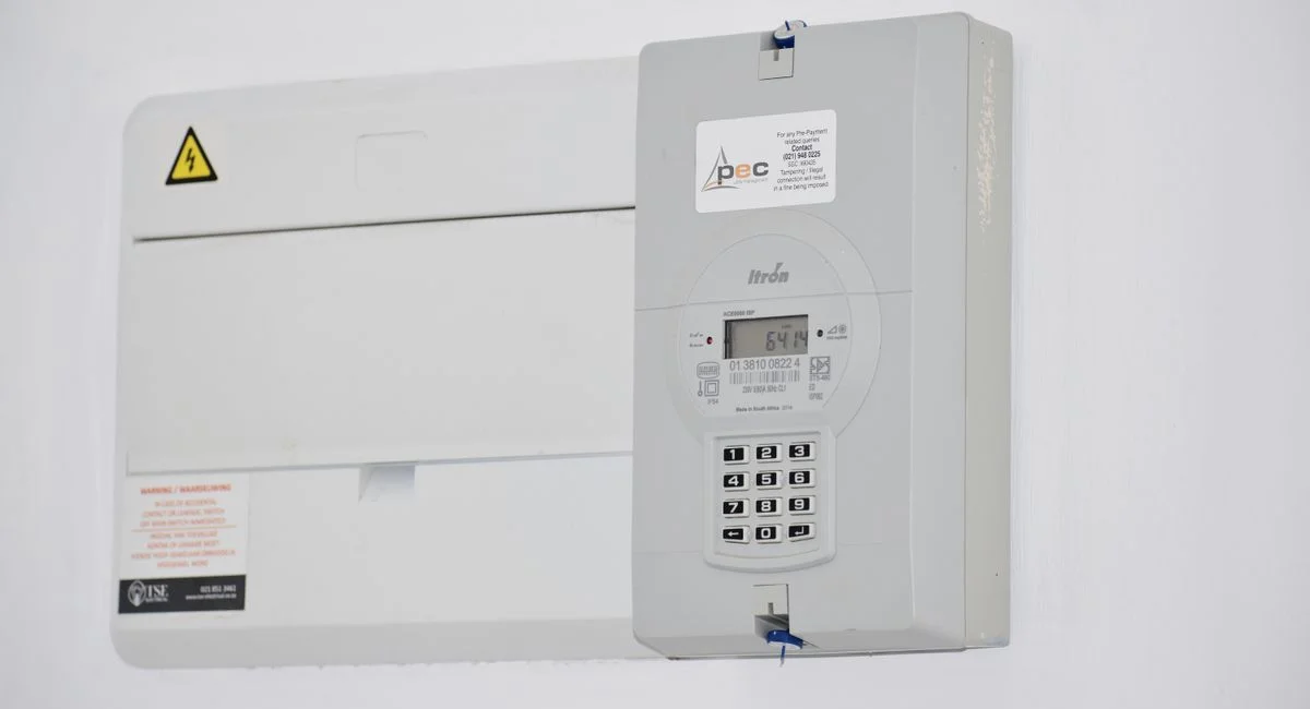 Electrical meter and fuse box on a white wall in Cape Town, South Africa, for energy monitoring or billing.