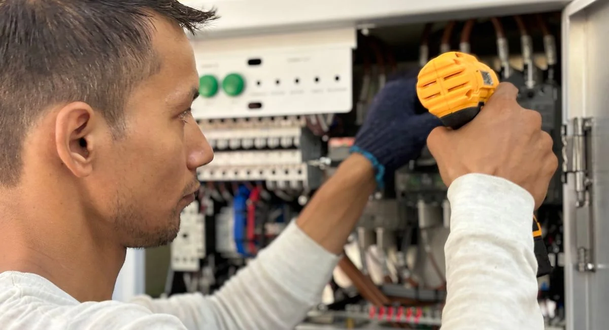 Focused technician using a drill on an electrical panel, showcasing expert workmanship.