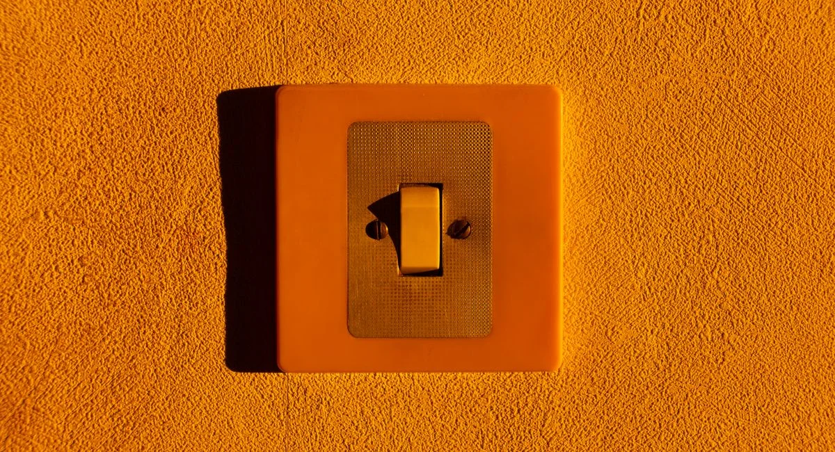 Close-up of a yellow light switch on a textured wall, highlighting minimalism.